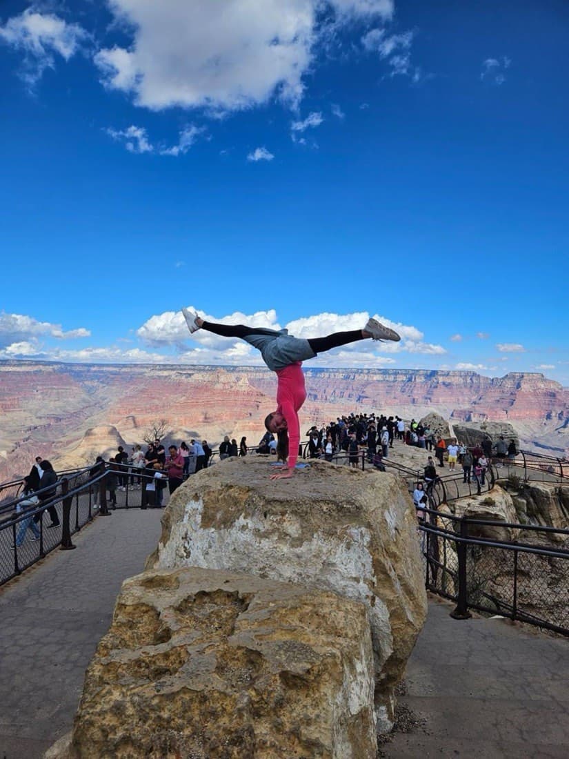 A gymnast doing a split handstand at the Grand Canyon