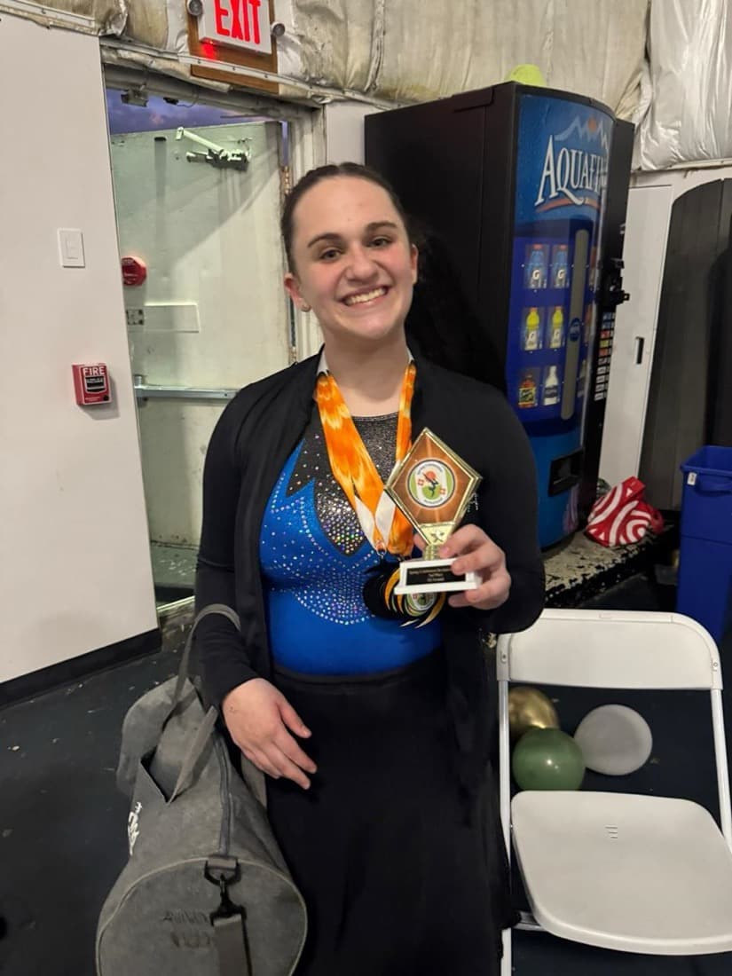 A gymnast with a medal and trophy after a meet